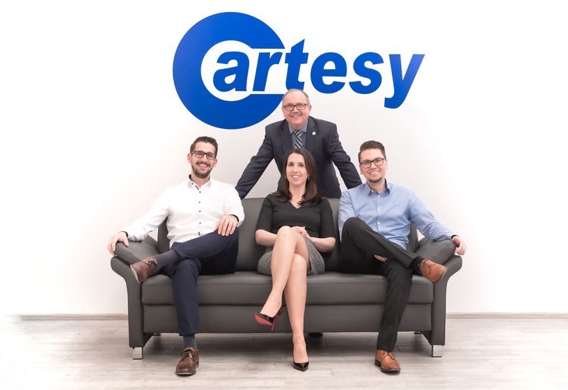 Cartesy Mitarbeiter auf einer Couch mit blauen Cartesy Logo im Hintergrund